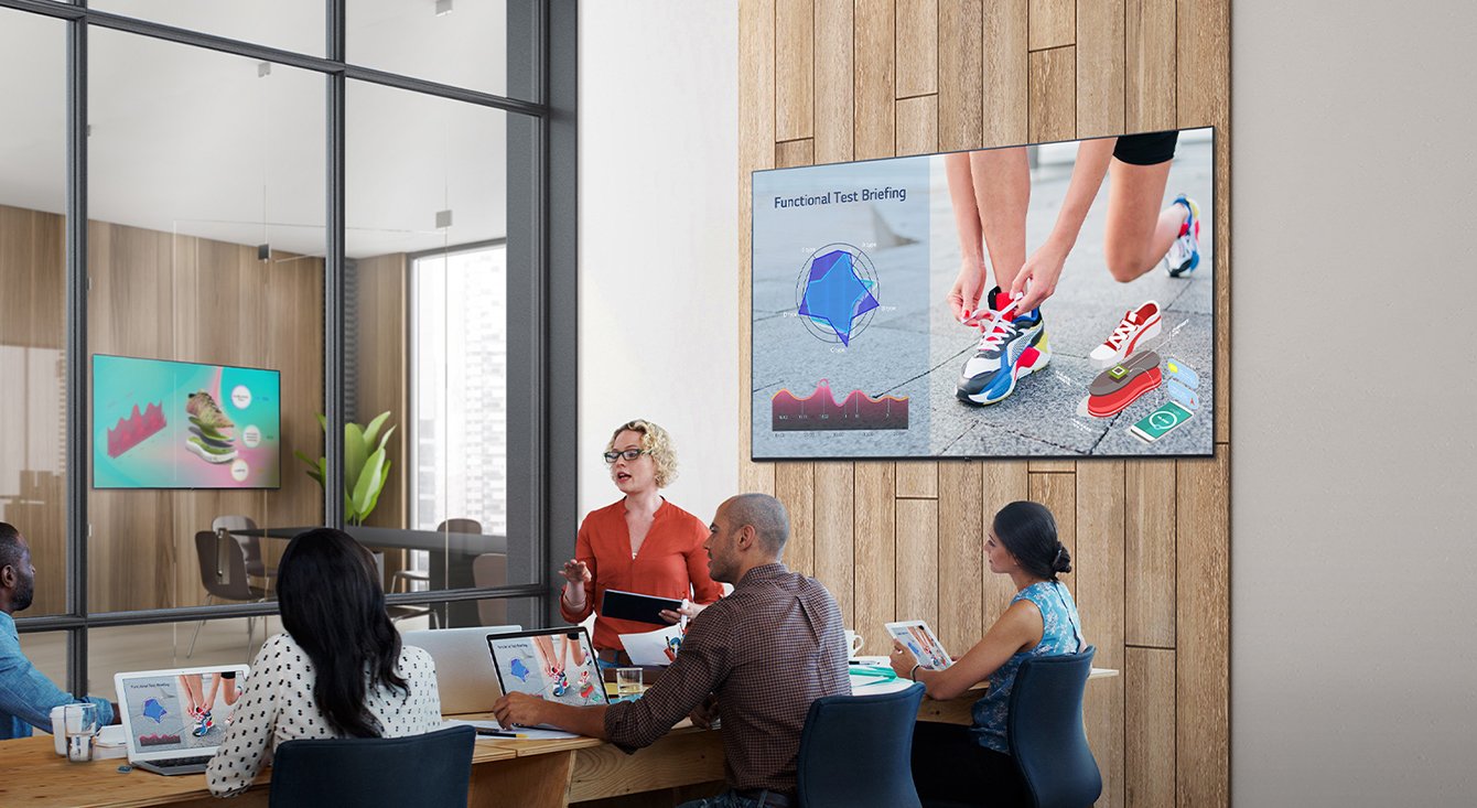 Five people in a meeting room with 65 inch 4K UHD Signage (SKU: 65UL3J-B) on the wall